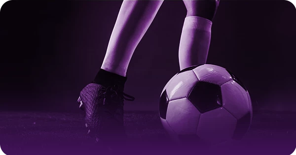 Aposta Mais de 0.5 Gols. Imagem ilustrativa para guia de apostas esportivas da H2bet, focada nas pernas de um jogador controlando a bola no gramado, com filtro roxo e foco na explicação do mercado de over gols.